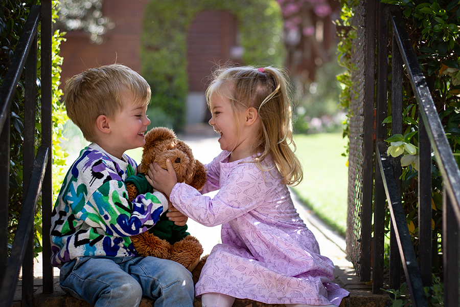 sister and brother playing with teddy